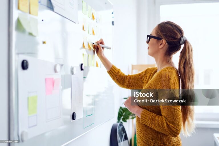 Young woman working in startup office writing on whiteboard