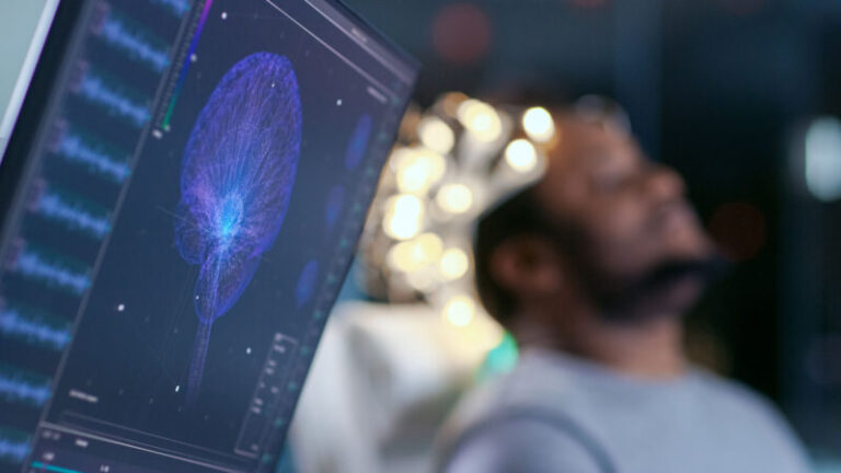 Monitors Show EEG Reading and Graphical Brain Model. In the Background Laboratory Man Wearing Brainwave Scanning Headset Sits in a Chair with Closed Eyes